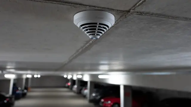 Bosch automatic fire detector installed on the ceiling of a large underground parking garage