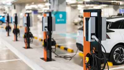 a row of electric cars are charging inside an indoor parking garage
