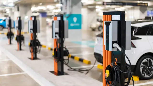 a row of electric cars are charging inside an indoor parking garage