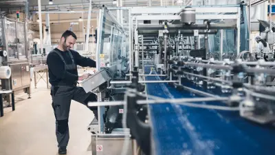 factory worker inside a manufacturing plant controlling a conveyor belt