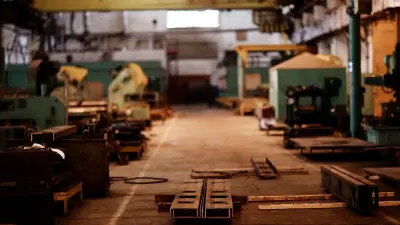 Text: unfocused image of an warehouse with pallets and machinery.