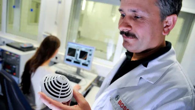 A Bosch employee in a fire laboratory holding a AVENAR detector 4000 series.