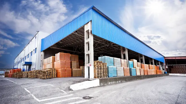 a half-open warehouse is full of stacked pallets