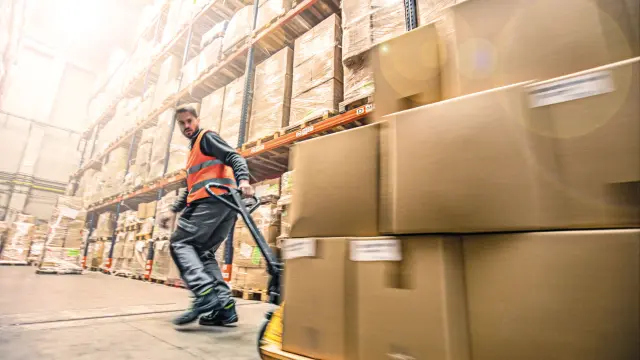worker in a warehouse pulls boxes in a forklift