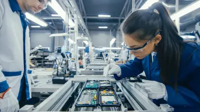 Two employees working at a production line with electrical and electronic components